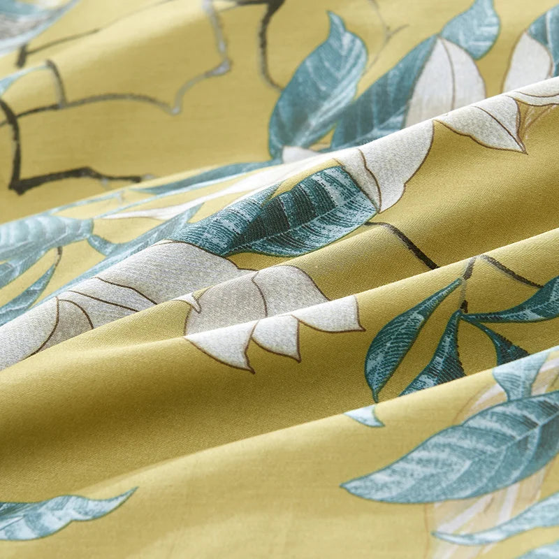 Close-up of yellow fabric with green leaf print from the Imperial Bloom Bedding Set, crafted from Silky Egyptian Cotton for a soft, breathable feel and vibrant, nature-inspired design.