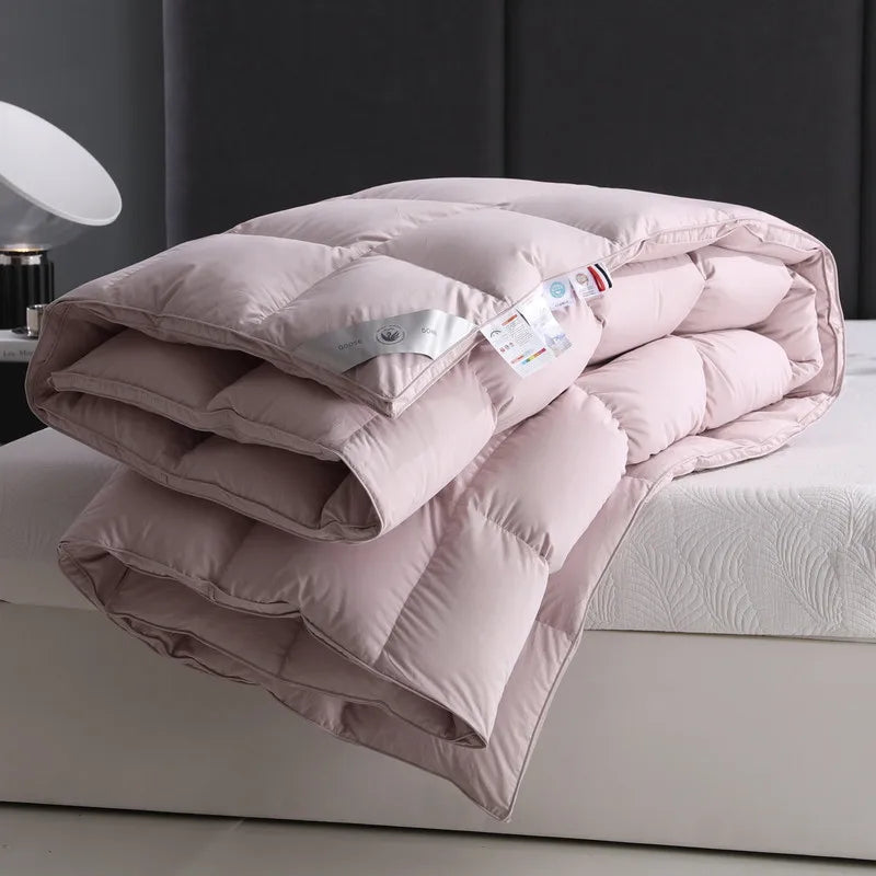 Close-up of a soft light pink, 100% cotton duvet neatly folded on the bed. Filled with premium white goose down, it offers a fluffy, breathable texture, and the solid color design adds a serene, inviting touch. Available in Queen and King sizes.