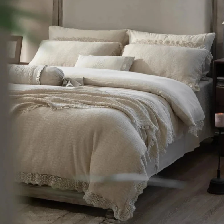 Corner view of a beautifully made bed featuring a soft cotton linen bedding set with ecru-colored pillows and elegant lace accents.