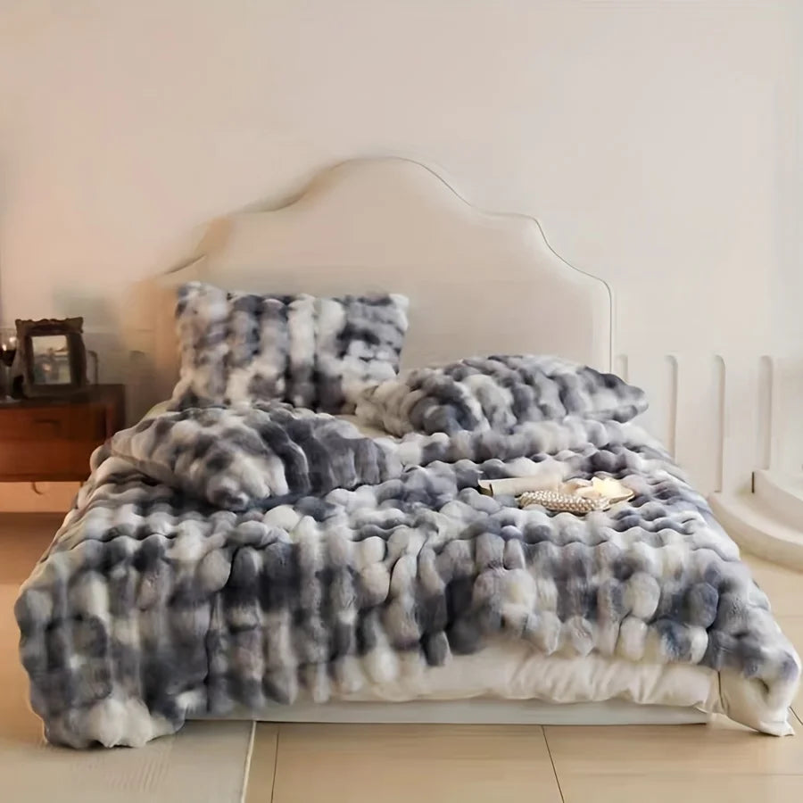 Dream Faux Fur Tie-Dye Blanket draped over a bed in grey/blue and white. The ultra-soft, luxurious faux fur adds a touch of elegance and warmth to the bedroom, creating a cozy and stylish space for relaxation. Perfect for year-round comfort, this chic blanket elevates your decor with its sophisticated design.