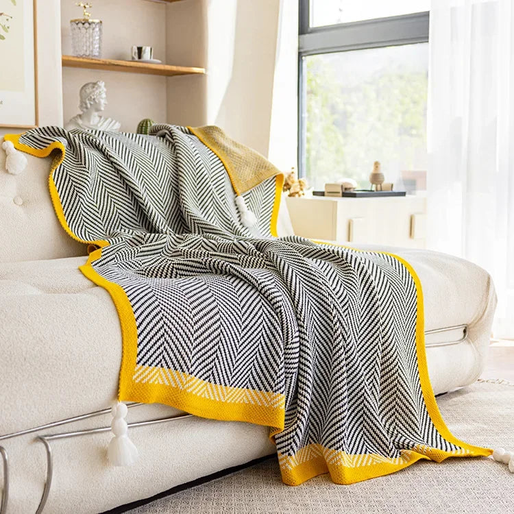 Nordic Throw blanket draped over a sofa, showcasing its sleek black and white design with yellow accents and detailed texture.