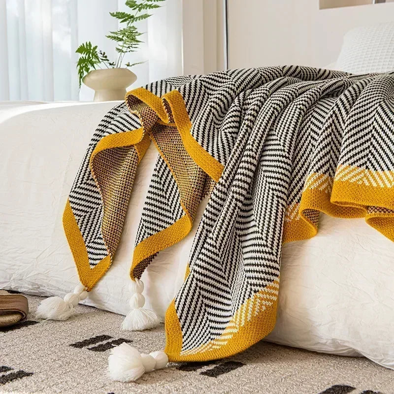 Nordic Throw blanket draped over a bed, showcasing its sleek black and white design with yellow accents