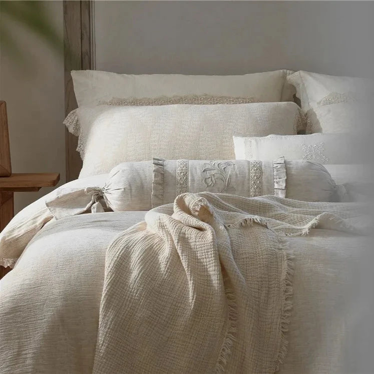 Detail of a beautifully made bed with ecru-colored pillows, soft cotton linen duvet cover, and breathable fabric for a cozy, elegant look