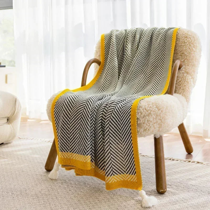 Nordic Throw blanket draped over a chair, showcasing its sleek black and white design with yellow accents