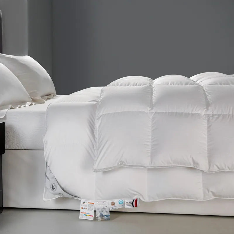 Side view of the Seraph comforter in white, crafted from 100% cotton with an 80 fabric count. The soft, breathable comforter is filled with premium white goose down, offering warmth and a fluffy, cloud-like texture. Its elegant solid color design showcases durability and comfort, making it a perfect addition to any bedroom. Available in Queen and King sizes.