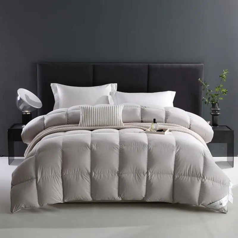 Solace comforter in gray, neatly folded on the bed. Made from soft, 100% cotton with an 80 fabric count, it’s filled with premium white goose down for a breathable, fluffy texture. The solid color design offers both elegance and durability, making it the perfect addition to any bedroom. Available in Queen and King sizes.