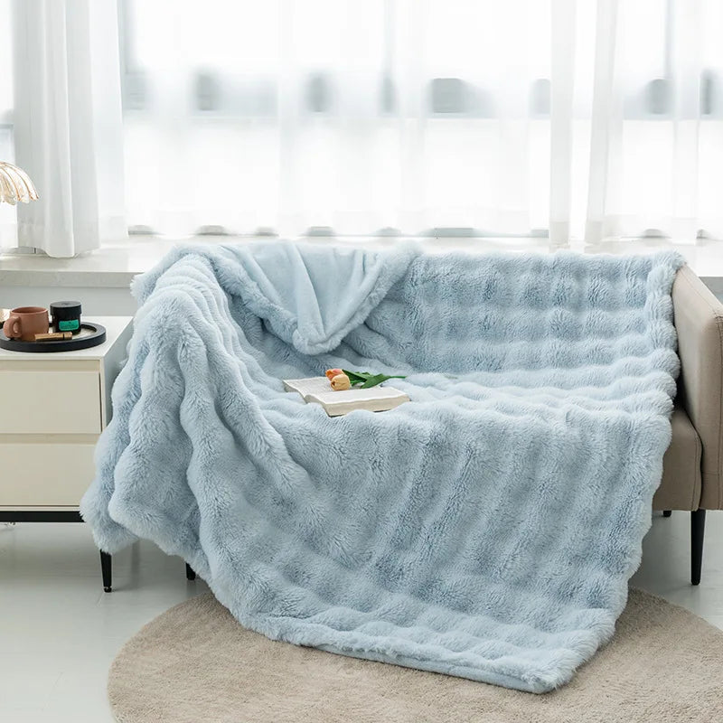 Cocoonette Rabbit Plush Blanket in light blue over a sofa, offering ultimate warmth and comfort, perfect for adding elegance and relaxation to any room.