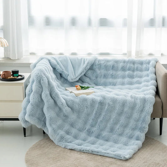 Cocoonette Rabbit Plush Blanket in light blue over a sofa, offering ultimate warmth and comfort, perfect for adding elegance and relaxation to any room.