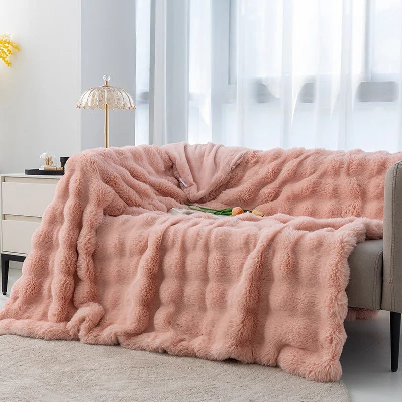 Cocoonette Rabbit Plush Blanket in soft peach pink, elegantly draped over a sofa, providing luxurious warmth and comfort while adding a touch of style and coziness to any space.